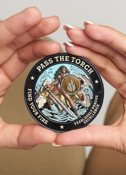 TORCH x Shark Tank challenge coin held between hands, featuring warrior artwork.